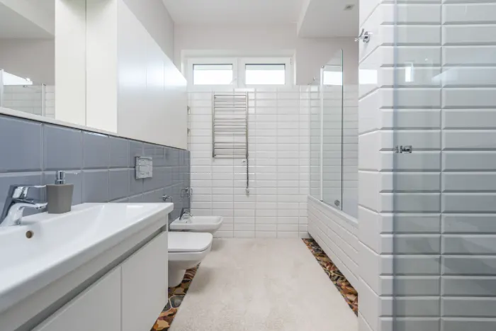 Baño alicatado en blanco con dos lavabos, ducha con mampara y luz natural